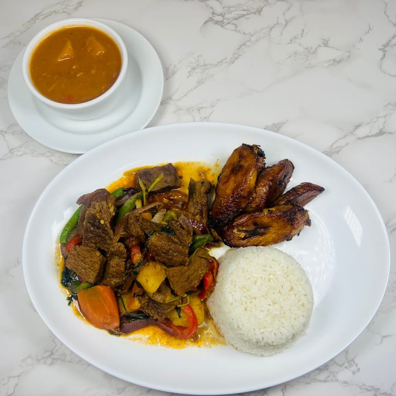 Plaza Restaurant's beef and vegetable dish with rice, plantains, and a side of soup.