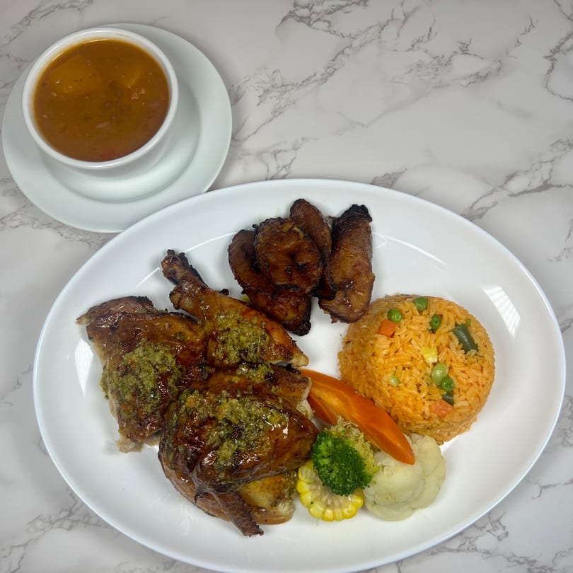 Plaza Restaurant's roasted chicken with green sauce, rice, plantains, and vegetables, with a side of soup.